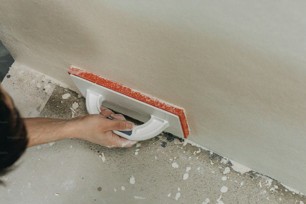 Hand applying drywall joint compound with a sanding tool on wall.