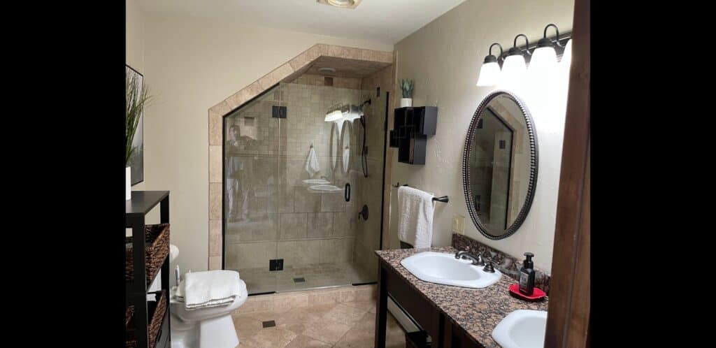 Modern bathroom with glass shower, double sink, and elegant decor.
